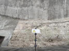 Electric wire fence with warning sign installed in zoo enclosure for dangerous animals, providing protective barrier that ensures visitor safety and prevents predators from escaping confined area photo