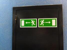 Universal exit signs with running figure and directional arrows illustrate internationally recognized emergency guidance system, offering nonverbal clarity across cultures in public buildings photo