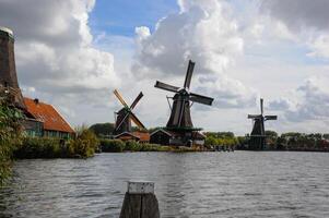 Historic Dutch windmills in the Netherlands, once known as Holland, with billowing clouds in the backdrop. photo
