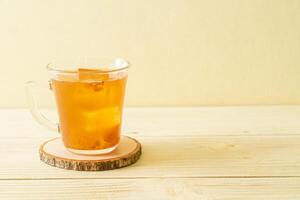 Delicious sweet drink tamarind juice and ice cube on yellow wooden background photo
