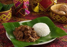 Indonesian Rendang Beef with Rice A Culinary Delight Served on Banana Leaf with Traditional Decor photo