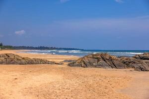 Sunny tropical beach with rocks and turquoise ocean in Sri Lanka 1 photo