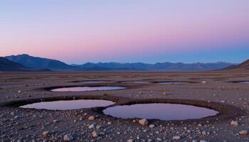 a flat, rocky plateau with shallow pools reflecting the twilight sky, surrounded by distant mountain peaks tinged with purple. photo
