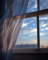 A window with a curtain and a view of the sky photo