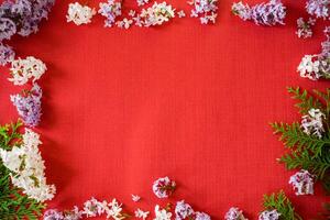 Floral frame of white and purple lilac with empty space on red background photo