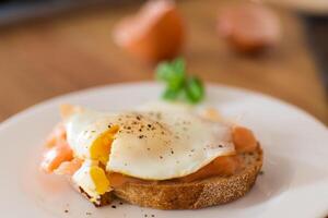 A delicious simple breakfast. A slice of bread with a cooked egg and lightly salted red fish photo