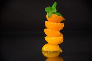 Canned apricot slices. Ripe peach halves in syrup on black background photo