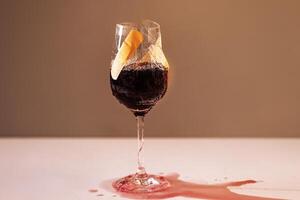 Close-up of a cracked glass of red wine. A broken goblet of bright juice covered with a plaster. A leaking cup with a red drink. photo