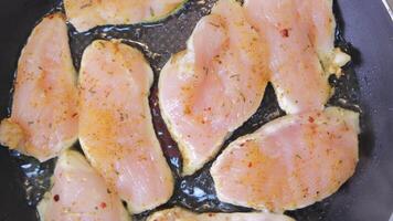 Raw chicken fillets frying in pan with spices, close-up view of seasoned meat, cooking process video