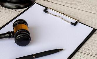 Side view of blank white paper clipboard with customizable space for text and with gavel next to it. Copy space concept. photo
