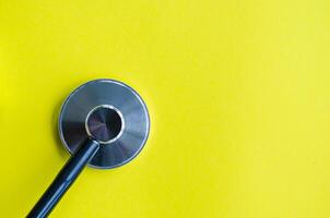 A stethoscope placed on a bright yellow background with customizable space for text. photo
