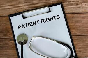 Top view of Patient Rights Text on white paper clipboard with stethoscope on wooden table background. Health and medical concept. photo