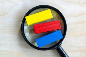 Top view of multicolored wooden blocks with magnifying glass with customizable space on wooden block for text photo
