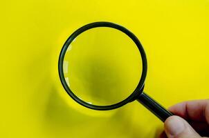 Top view of a magnifying glass against a bright yellow background. Searching, examining, focusing or investigation concept.. photo