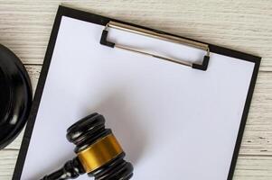 Top view of a blank white paper clipboard with customizable space for text and with gavel next to it. photo