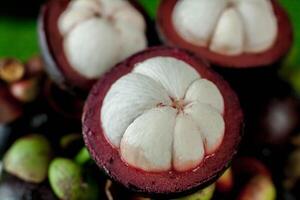 10 Fresh mangosteen fruits and cross section showing the thick purple skin and white flesh. photo