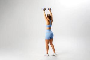 Fitness enthusiast performing overhead dumbbell exercise in a studio setting during a workout session photo