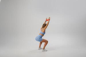 Fitness enthusiast demonstrating a squat exercise in a spacious studio setting while wearing workout attire photo