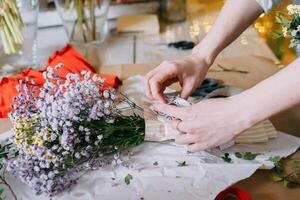 florist work on preparing beautiful floral arrangement. Various flowers and materials lie on table, emphasizing the artistic and inspiring atmosphere associated with floral design photo