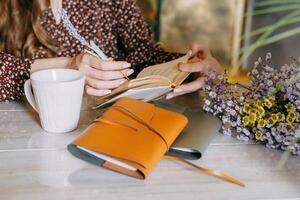 Woman enjoys reading at cozy table with floral notebook and warm coffee photo