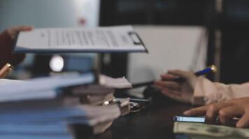 Two people sitting at a desk with papers and money video