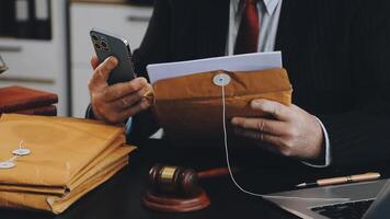 A man in a suit is using his phone to look at documents video