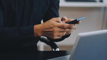 A man using his cell phone while sitting at a desk video