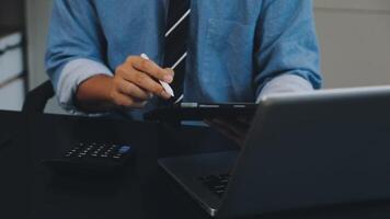 une homme dans une attacher est en utilisant une stylo et une calculatrice video
