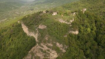 Aerial ancient Bochorma fortress complex in Georgia surrounded by scenic Caucasus mountains. Medieval site features stone fortifications, domed church, panoramic over Iori River valley video