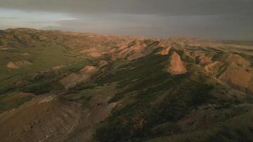 Aerial fly over rainbow or red mountains, colorful layers of the Rainbow Mountains in Georgia,Caucasus region. The striking mineral patterns, rolling hills form surreal, painterly landscape from above video
