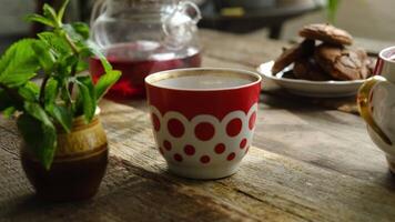 Tea cup with red and white polka dots on table. Morning breakfast with tea and cookies. video