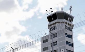 Low Angle View of Air Traffic Control Tower Behind Barbed Wire Fence. photo