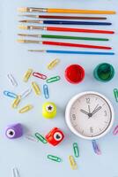 Creative back to school supplies flatlay with colorful markers paint brushes toy bus clock clips paper punches and vivid paperclips symbolizing learning routine education and artistic expression photo