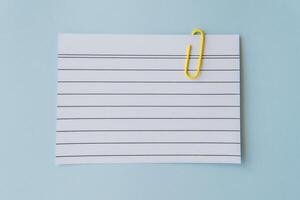Minimal school paper concept with lined sheet and yellow paperclip on blue background symbolizing writing planning simplicity schoolwork education mood and creative organization for students photo