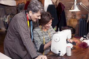 expert seamstress teaching an apprentice how to work the sewing machine photo