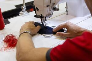 Men's hands near the sewing machine hold a cloth, in the process of sewing photo