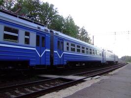 Blue train cars on a railway track in a quiet station during early photo