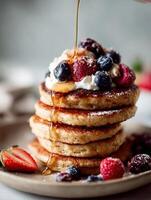 Fluffy pancakes with berries and maple syrup photo