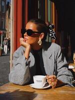 Stylized digital painting of a fashionable woman sitting at an outdoor cafe table. photo