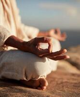 Realistic photo in serene sunrise style. Close-up of a womans hand resting on her knee in a Gyan mudra pose during seated meditation.