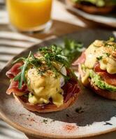 Realistic food photography in film style eggs Benedict on toasted bun with prosciutto, creamy hollandaise sauce, avocado mash and microgreens on top. photo