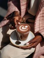 Womans hands with manicured nails holding a latte with heart-shaped latte art. photo