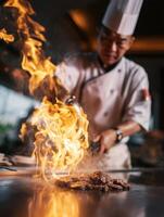 A chef in a tall white hat performs a dramatic cooking act on a teppanyaki grill, pouring liquid that instantly bursts into flames. photo