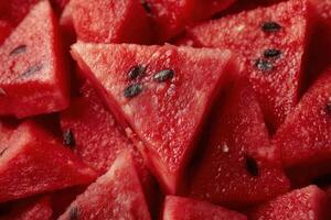 Macro close-up of triangular slices of juicy red watermelon with dark seeds. photo