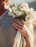 Close-up of a womans hand with a sapphire engagement ring resting on a mans shoulder. photo