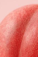 Ultra macro shot of the surface of a ripe peach covered in tiny water droplets, high detail texture of fuzzy red-pink skin, photographed in soft studio light against a pastel pink background photo
