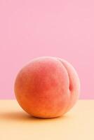 Minimalist studio shot of a single ripe peach standing upright on a flat pastel orange surface, against a soft pink background, high-resolution macro photography photo