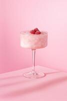 A delicate frozen raspberry dessert served in a tall elegant cocktail glass with a transparent stem, topped with whole raspberries covered in frost. photo
