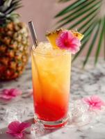 Tropical cocktail in a tall clear glass with gradient colors from red to orange, topped with a pineapple slice, vibrant pink flower, and metal straw. photo