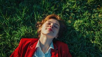 a young businesswoman is relaxing lying on the grass field to relieve the tiredness of busy work. Shoot from above photo